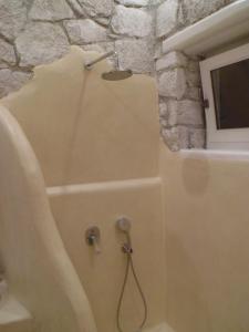 a shower in a bathroom with a stone wall at Milo Milo Suites in Mandrakia
