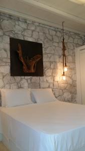 a bedroom with a white bed with a stone wall at Milo Milo Suites in Mandrakia