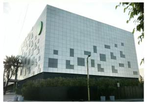 マニラにあるGreen Sun Hotelの緑の看板が立つ白い大きな建物