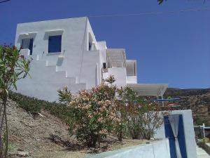 a white building with stairs on top of a hill at Agnanti Apartments in Vathi
