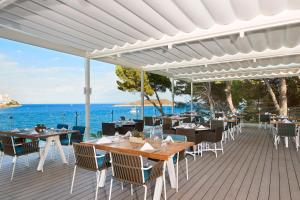 un restaurante con mesas y sillas y el océano en Meliá Calviá Beach en Magaluf