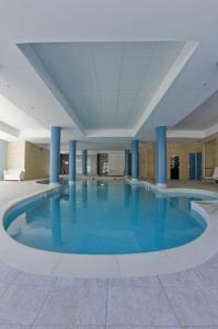 a large swimming pool in a building with blue columns at Noemys Terrasses de Labrau in La Foux