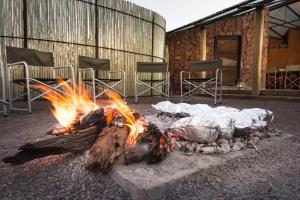 eine Feuerstelle vor einem Gebäude mit Stühlen in der Unterkunft Etendeka Mountain Camp in Damaraland