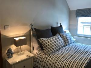 a bed with a striped comforter and a lamp on a table at The Old Post Office in Bridgnorth