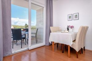 a dining room with a white table and chairs and a window at Anchor Apartments in Stari Grad