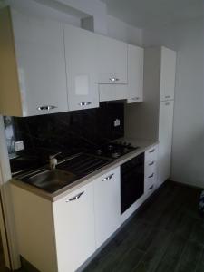 a kitchen with white cabinets and a stove and a sink at Holiday Apartmant in Primošten