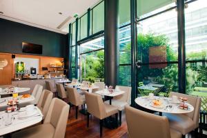 a restaurant with white tables and chairs and windows at Residhome Bois Colombes Monceau in Bois-Colombes