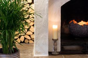 a candle sitting next to a fireplace with a plant at Hipping Hall in Cowan Bridge