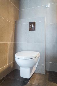 a bathroom with a white toilet in a tiled wall at Villa Velvet in Villeneuve-Loubet