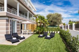 a patio with lounge chairs and a lawn in front of a building at Villa Velvet in Villeneuve-Loubet