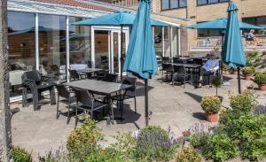 a patio with tables and chairs and umbrellas at Hotel 6400 in Sønderborg