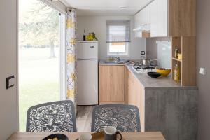 a kitchen with a refrigerator and a table with chairs at Camping Les Chênes Verts in Meschers-sur-Gironde