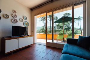 a living room with a couch and a television and a balcony at Residence Renaione in Punta Ala