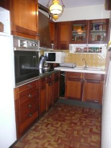 eine Küche mit Holzschränken und einem Herd mit Backofen in der Unterkunft Residence les Goelands in Jullouville-les-Pins