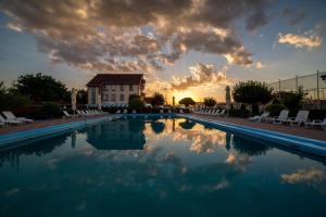 a large swimming pool with a sunset in the background at Motel Darina in Ungheni