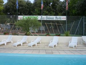 een groep witte stoelen naast een zwembad bij Camping Les Chênes Verts in Meschers-sur-Gironde