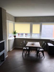 - un salon avec une table, des chaises et des fenêtres dans l'établissement Apartament Birutes 22, à Klaipėda