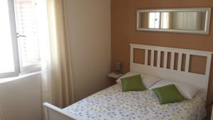 ein Schlafzimmer mit einem Bett mit zwei grünen Kissen in der Unterkunft Villa Lasta in Drašnice