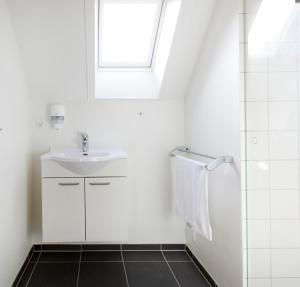 ein weißes Bad mit einem Waschbecken und einem Fenster in der Unterkunft Hotel Residens Møen in Stege