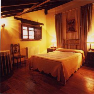 a bedroom with a bed and a window and a chair at El Ama De Llaves in Hontoria