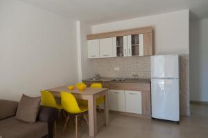 eine Küche mit einem Tisch mit gelben Stühlen und einem Kühlschrank in der Unterkunft Del Mar Apartments in Čanj