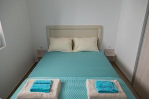 a bed with blue sheets and two towels on it at Del Mar Apartments in Čanj