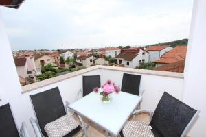 a white table with chairs and a vase of flowers on a balcony at Apartments Tanja in Rovinj