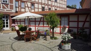 un patio con sombrilla, mesa y sillas en Pension Mühlrad, en Herbsleben