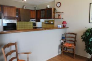 eine Küche mit Holzschränken und einer Theke mit zwei Stühlen in der Unterkunft Residence les Goelands in Jullouville-les-Pins + 1 Foto