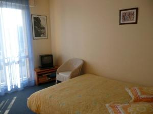 1 dormitorio con 1 cama, 1 silla y TV en Residence les Goelands, en Jullouville-les-Pins