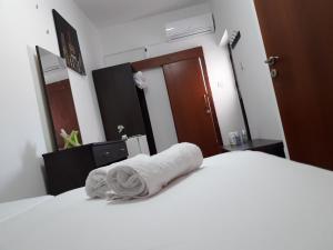 a bedroom with a white bed with a towel on it at Marina's Rooms in Larnaca