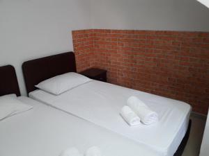 a bed with two white pillows and a brick wall at Marina's Rooms in Larnaca