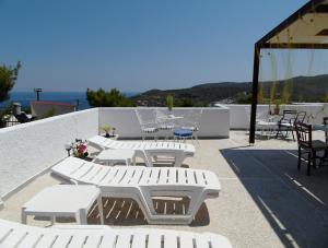 un grupo de mesas y sillas blancas en un patio en Eri Studios, en Agia Marina Aegina