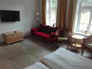 een woonkamer met een rode bank en een tafel bij Gasthaus Wagner in Golzow