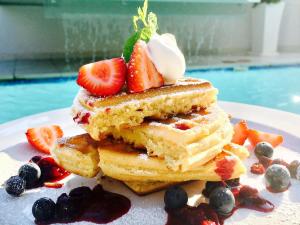 
a white plate topped with pancakes and strawberries at The Glen Boutique Hotel & Spa in Cape Town
