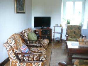 - un salon avec un canapé et une télévision dans l'établissement Kerbarbo, à Plouagat