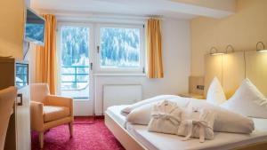 una camera da letto con un letto, una sedia e una finestra di Haus Battisti a Sankt Anton am Arlberg