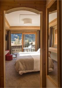 a bedroom with a bed and a large window at Hotel le Petit Dru in Morzine