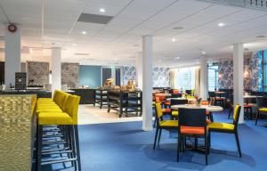 a restaurant with yellow chairs and tables and a bar at Thon Hotel Tønsberg Brygge in Tønsberg