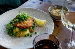 um prato de comida numa mesa com um copo de vinho em Hotel Lilla Roberts em Helsinque