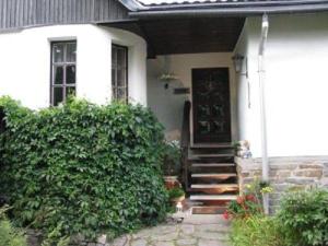 una casa bianca con portico e porta di Ferienhaus-Landmann a Tannenberg