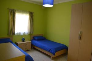a green bedroom with two beds and a window at The April Maisonette in Marsaskala