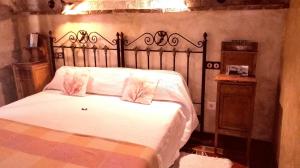 una camera da letto con un letto con lenzuola bianche e cuscini rosa di Hotel Rural La Enhorcadora a Portillo