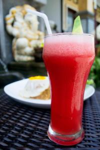 a drink sitting on a table with a plate of food at Wijaya Guesthouse in Canggu