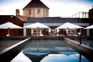 einem Pool mit Sonnenschirmen vor einem Gebäude in der Unterkunft Hotel España Ramblas in Barcelona