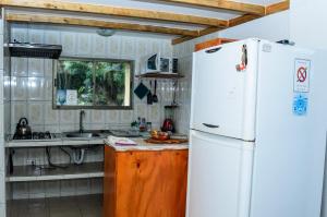 La cuisine est équipée d'un réfrigérateur blanc et d'un évier. dans l'établissement Cabañas MANA NUI INN, à Hanga Roa