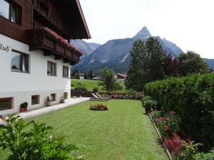 un cortile verde con un edificio e montagne sullo sfondo di Haus Karl's Ruh a Ehrwald