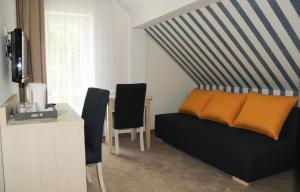 a living room with a bed and a desk with chairs at Ośrodek Wczasowy GAMA in Rewal