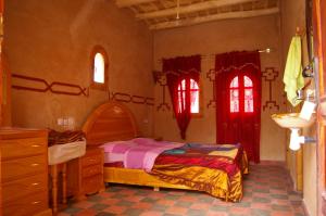 a bedroom with a bed and two windows at Auberge Des Jardins du Dades in Boumalne