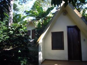 a small white house with a brown door at Chalés Sítio do Alemão in Ubajara